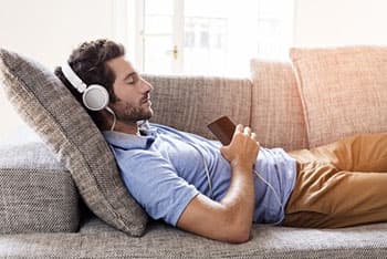 man on sofa listen headphones